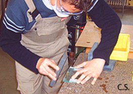 Ein Schüler ist am Glas schneiden. Dabei benutzt er ein entsprechendes Lineal und ein Werkzeug zum Ritzen des Glases.