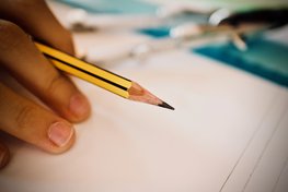 Hand hält Bleistift über einem Blatt Papier