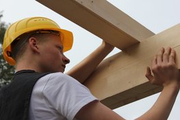 Das Bild zeigt einen Schüler, der ein Balken auf einem Rähmholz ausrichtet.