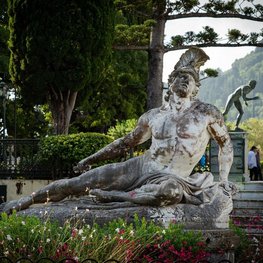 Eine Statue mit Kriegerhelm liegt, im Hintergrund steht eine weitere.