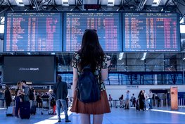 Eine Frau betrachtet die Abflugtafel am Flughafen.