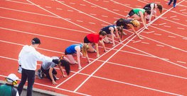 Mehrere Schülerinnen sitzen im Startblock auf der Laufbahn