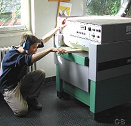 Ein Schüler arbeitet an einer Dickenhobelmaschine. Er schiebt ein Brett in die Maschine.