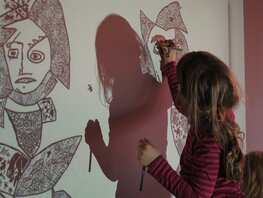 Ein Mädchen mal mit Hilfe eines Overheadprojektors ein großes, abstraktes Kunstwerk nach.