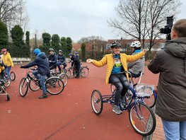 Ein Kameramann filmt eine Schulklasse beim Fahrradfahren auf einem Übungsplatz.